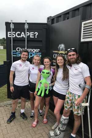Group of five people standing in front of container-based escape room