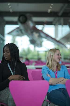 Two women sit on bright pink chairs at the Dyson challenge day with Challenger Escapes